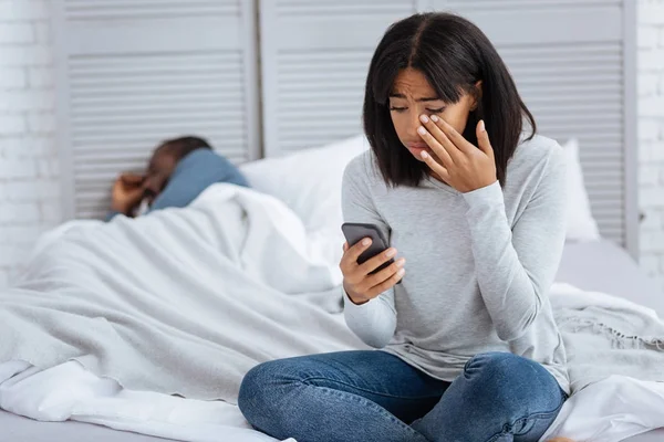 Mujer infeliz llorando mientras mira su teléfono inteligente —  Fotos de Stock