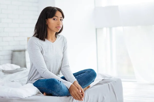 Mujer joven y relajada sentada en la cama — Foto de Stock