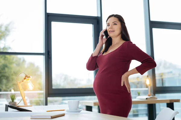 Талия радостной беременной женщины с телефоном — стоковое фото