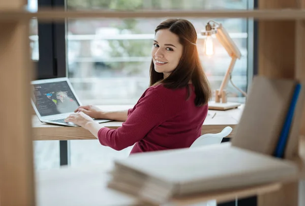 Lighthearted woman looking at you with a smile