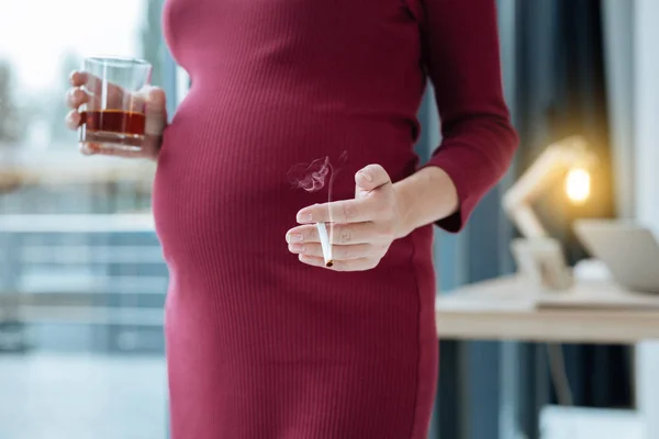Крупним планом вагітна жінка робить шкоду своїй майбутній дитині — стокове фото
