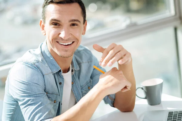 Morena alegre masculino sentado em seu local de trabalho — Fotografia de Stock