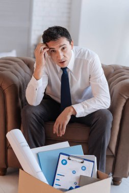 Bir koltukta oturan ve meraklı arıyorum ciddi genç adam