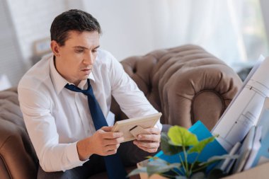 Oturma ve bir çerçeve içinde belgili tanımlık fotoğraf bakarak ciddi konsantre adam