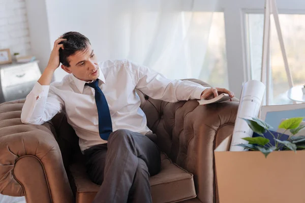 Вдумчивый молодой человек, сидя дома после потери работы — стоковое фото