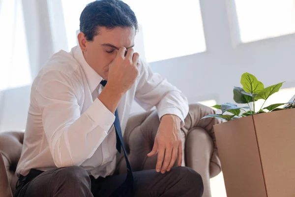 Exhausted sad man sitting with his eyes closed while having a headache — Stock Photo, Image