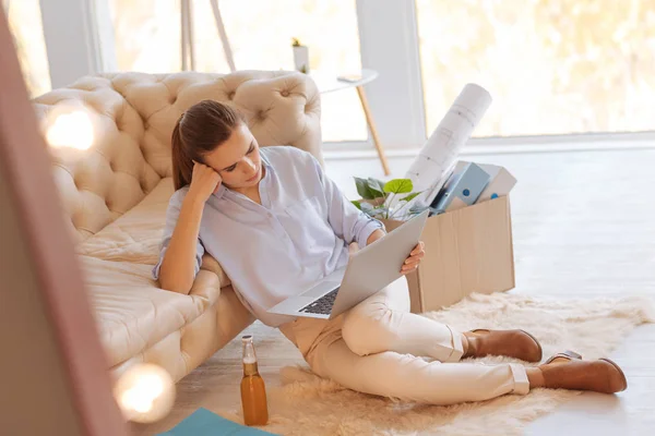 Ongelukkig moe vrouw de laptop kijken terwijl ze op de vloer — Stockfoto