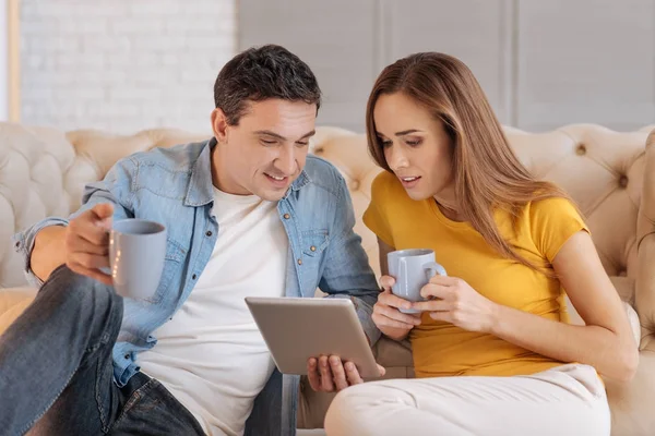 Emotional couple sitting drinking tea and watching an exciting film — Stock Photo, Image