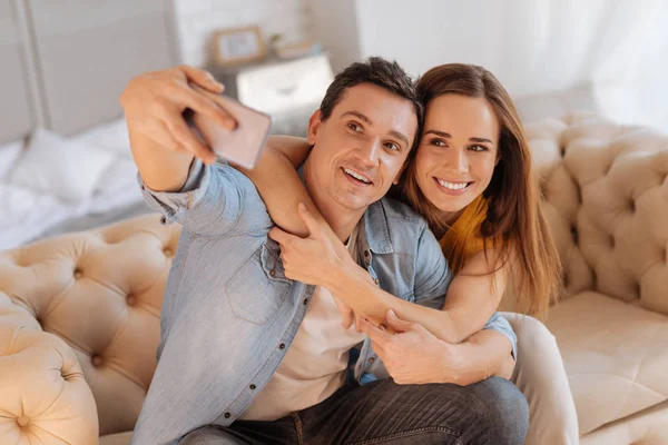 Lyckliga älskande par ta foton medan du sitter på en soffa — Stockfoto
