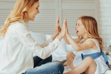 Neşeli güzel anne ve kızı alkışlayan bir oyun oynuyor