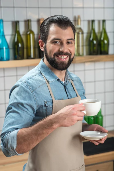 Uśmiechnięty młody kelner dobre samopoczucie podczas picia kawy w pracy — Zdjęcie stockowe
