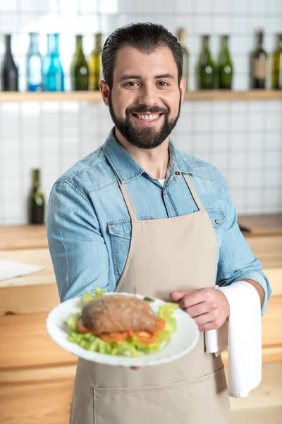 Emocionado camarero entusiasta sonriendo mientras muestra una comida sabrosa — Foto de Stock
