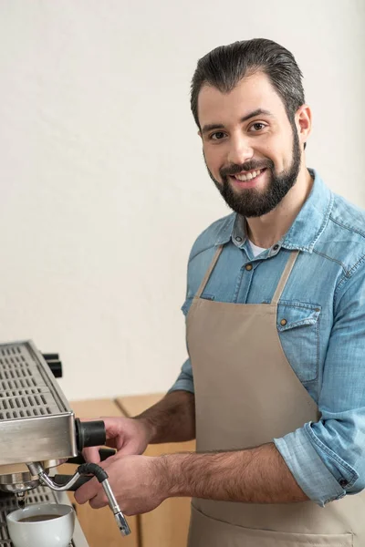 Agradable barman experimentado haciendo sabroso café y sonriendo — Foto de Stock