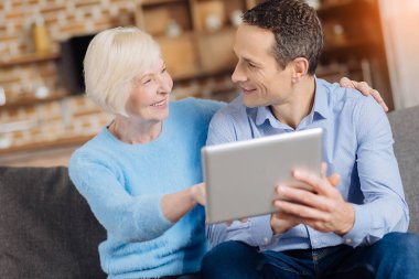 Neşeli yaşlı kadın oğlunu tablet hakkında danışmanlık
