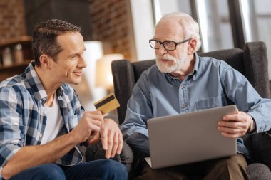 Dizüstü bilgisayar kullanarak babasının banka kartı veren genç adam