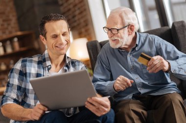 Genç adam ve yaşlı babası birlikte online alışveriş yaparken