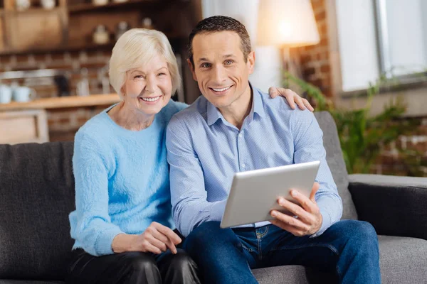 Усміхнена літня жінка і її син використовують планшет — стокове фото
