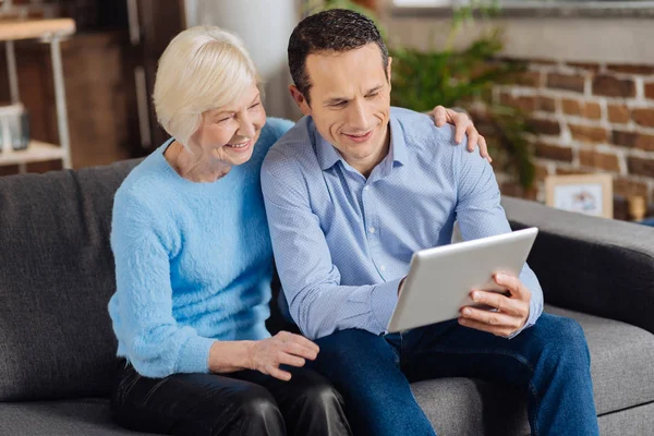 Oudere vrouw en haar zoon op zoek door middel van foto's op Tablet PC — Stockfoto