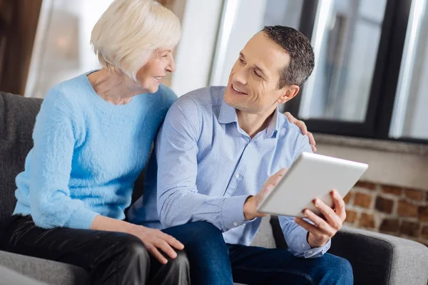 Чарівний чоловік і його старша мати розмовляють під час використання планшета — стокове фото