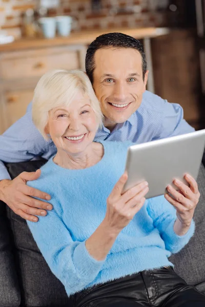 Cheerful senior mother and son posing while watching video — Stock Photo, Image