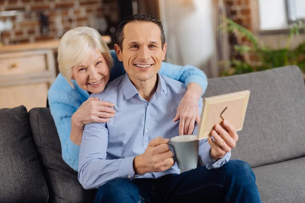 Mutlu anne ve oğlu çerçeveli fotoğrafa bakarken poz