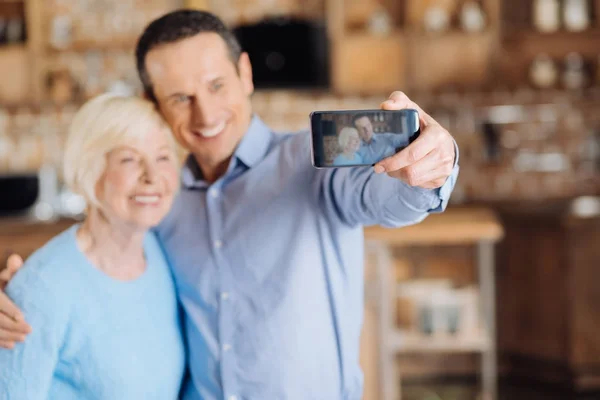 Kochającego syna biorąc selfie z matką osoby w podeszłym wieku — Zdjęcie stockowe