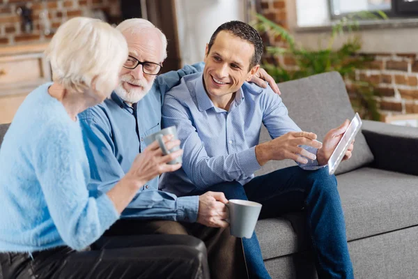 Happy family chatting on the couch while drinking coffee — Stock Photo, Image