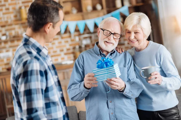 Feliz hombre mayor examinando su regalo recibido de su familia — Foto de Stock