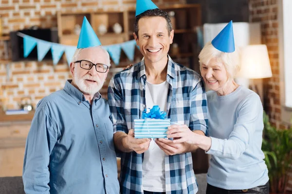 Familia alegre posando con una caja de regalo durante la fiesta de cumpleaños —  Fotos de Stock