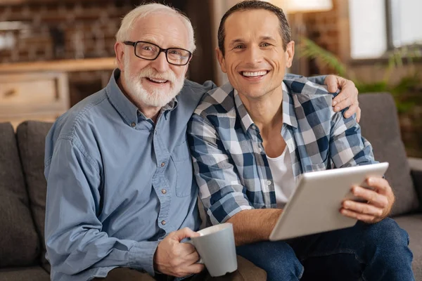 Upbeat hombre navegando por la web junto con su anciano — Foto de Stock