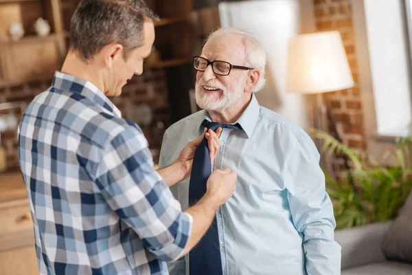 Caring man helping his elderly father tie his tie — Stock Photo, Image