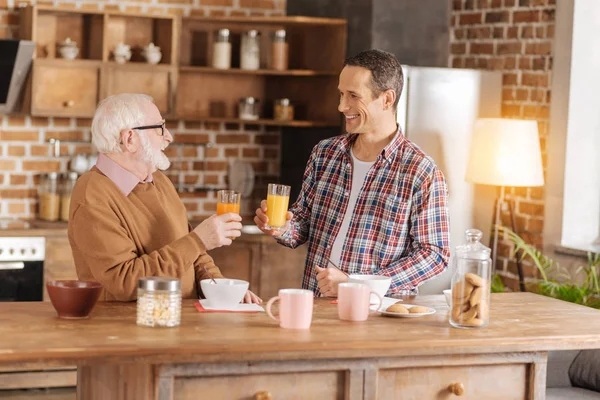 Encantador hombre y su anciano padre bebiendo jugo — Foto de Stock