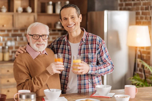 Alegre padre e hijo posando con vasos de jugo — Foto de Stock