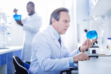 Ciddi akıllı bilim adamı mavi sıvıyı arıyorsunuz