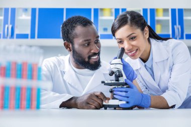 Bir mikroskop kullanarak memnun pozitif kadın