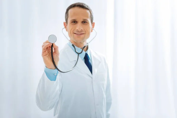 Blij arts met behulp van de stethoscoop terwijl u werkt — Stockfoto