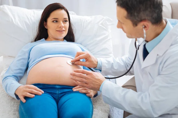 Веселая беременность, лежащая на диване в клинике — стоковое фото