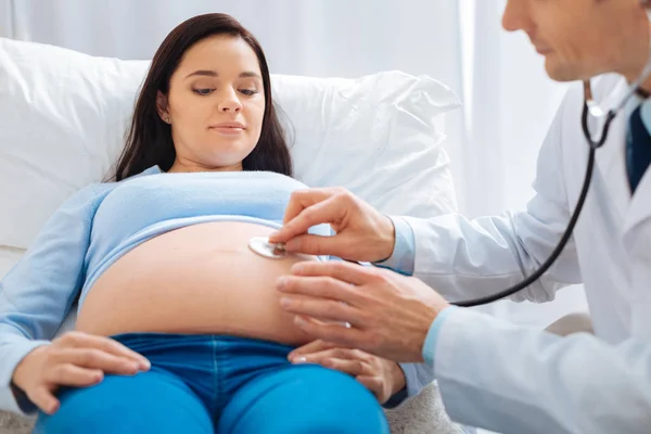 Gåtfulla ung kvinna tittar på hennes baby bump — Stockfoto