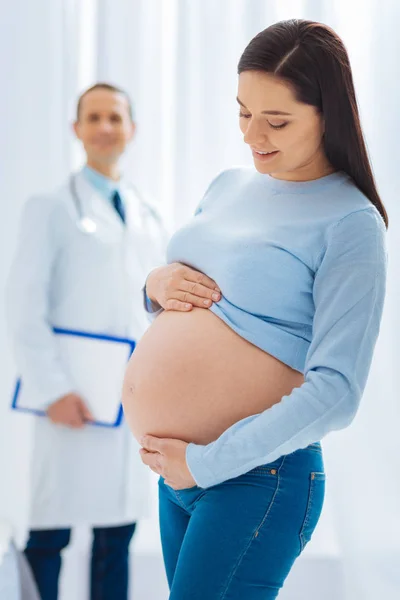 Gravidez encantada abraçando sua barriga — Fotografia de Stock