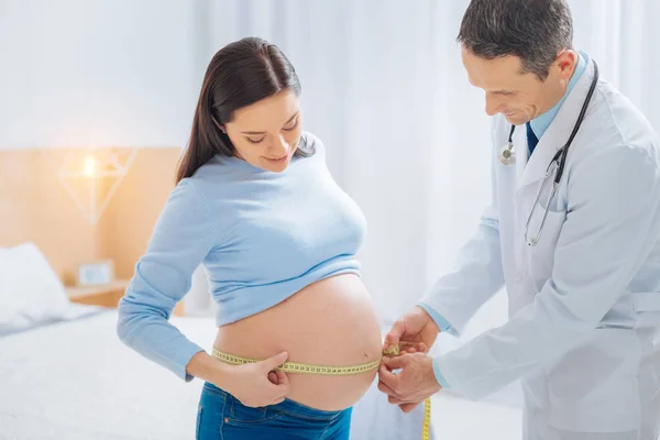 Při pohledu na její břicho dítě pozorný bruneta — Stock fotografie