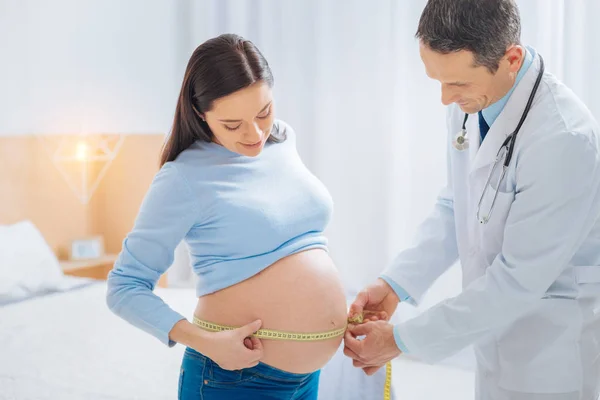 Aufmerksame Brünette schaut auf ihren Babybauch — Stockfoto