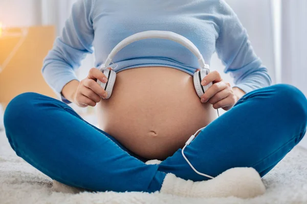 Close up van zwangere vrouw dat bedrijf hoofdtelefoon — Stockfoto