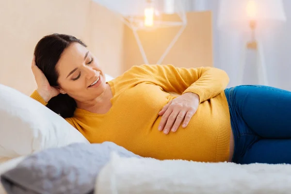 Entspannte Frau blickt auf ihren Babybauch — Stockfoto