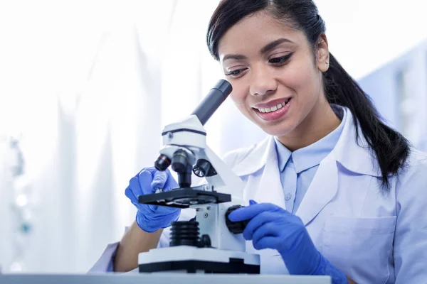Mulher alegre positivo olhando para o microscópio — Fotografia de Stock