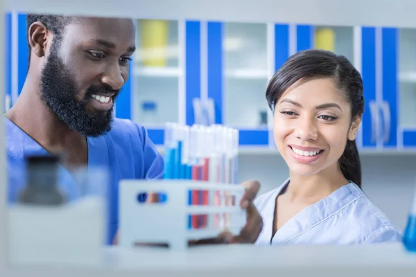 Nice joyful colleagues looking at the test tubes — Stock Photo, Image