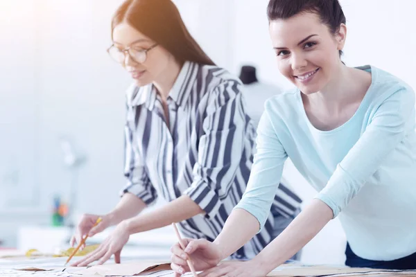 Jovens alfaiates sorridentes em seu local de trabalho no atelier — Fotografia de Stock