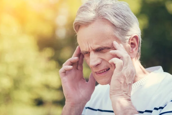 Fröhlicher älterer Mann, der unter Kopfschmerzen leidet — Stockfoto