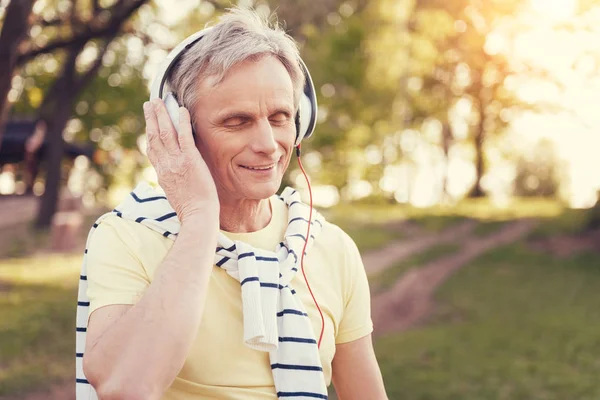 Kulaklıklar giyen memnun yaşlı adam
