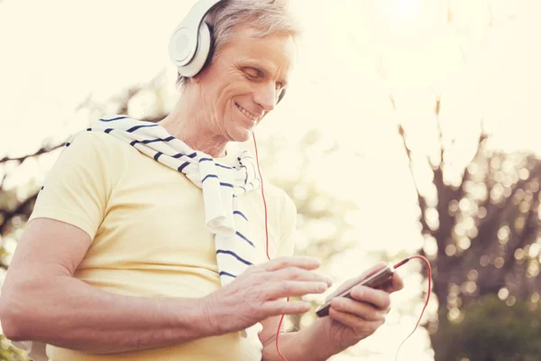 Joyful elderly man using an MP3 player — Stock Photo, Image