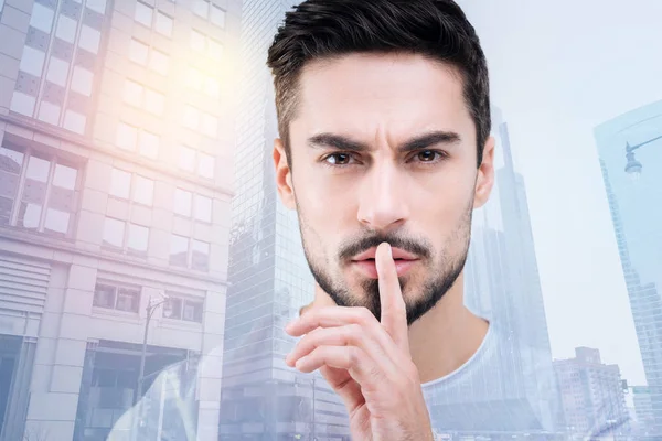 Attentive young man putting forefinger on his mouth — Stock Photo, Image